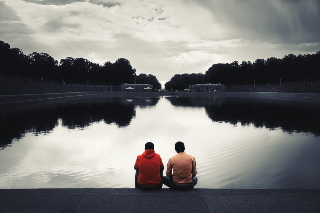 Zwei Männer sitzend von hinten am See des Völkerschlachtdenkmals in Leipzig (Colorkey)