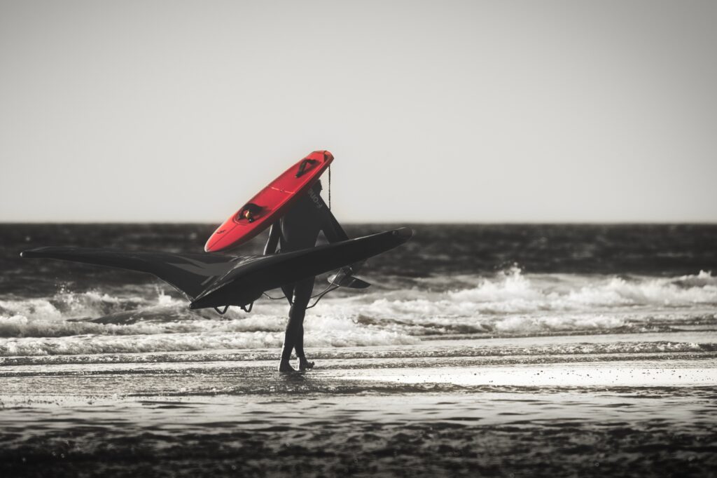 Surfer läuft am Strand mit rotem Surfbrett (Colorkey)