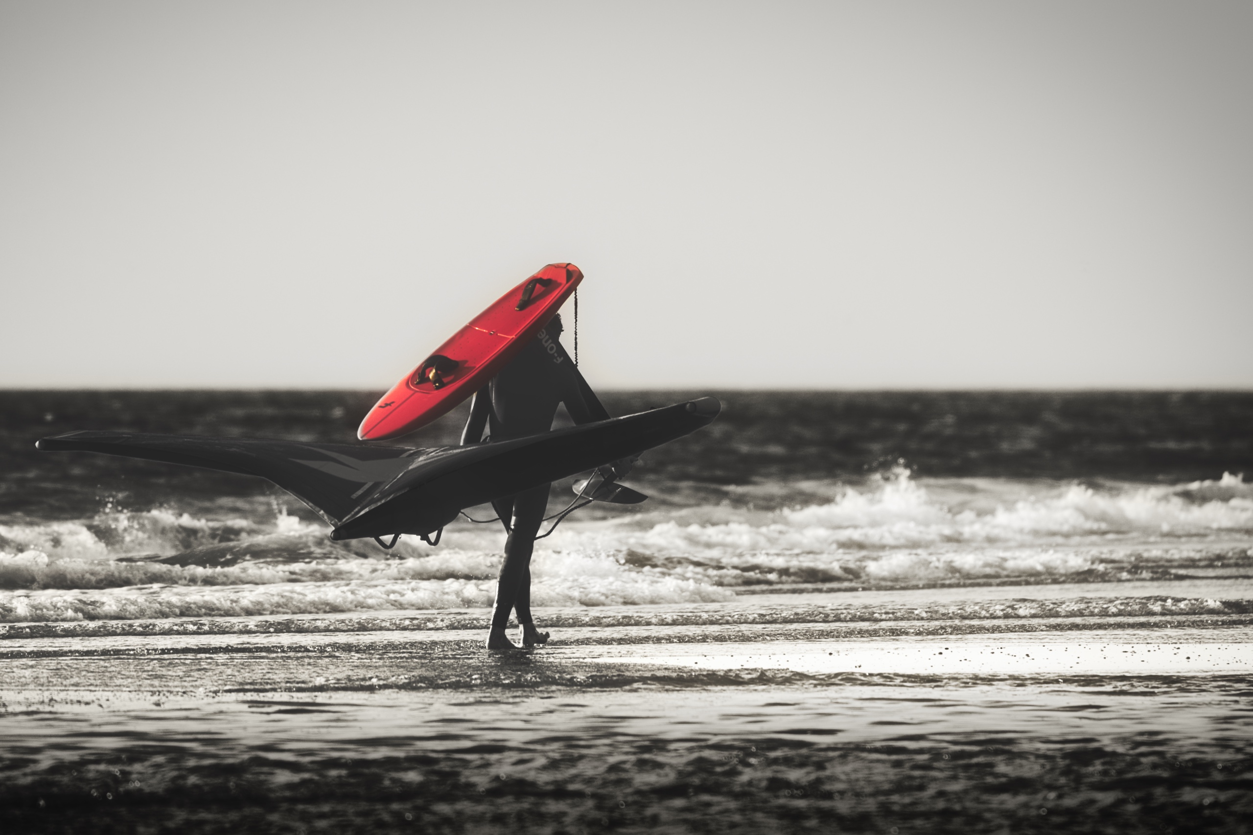 Surfer läuft am Strand mit rotem Surfbrett (Colorkey)