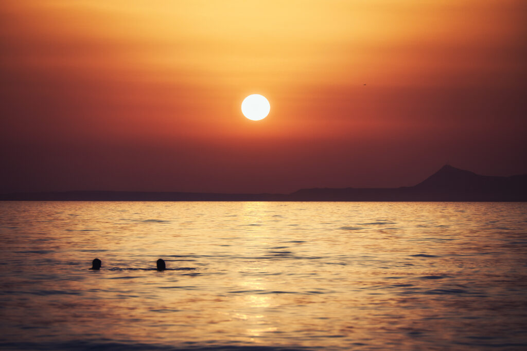 Zwei Badende am Adele Beach auf Kreta beim Sonnenuntergang
