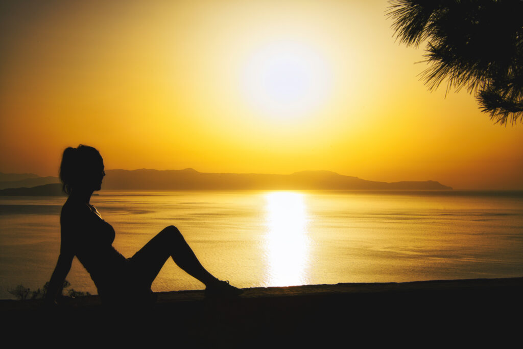Seitliche Silhouette einer Frau an der Küste Kretas bei Chania zum Sonnenuntergang