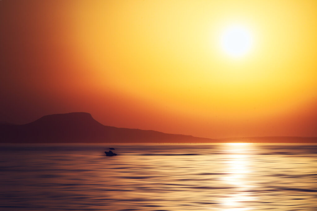 Kleines Motorboot an der Küste Kretas bei Rethymno zum Sonnenuntergang (Adamski Effekt)