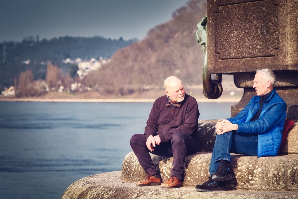 Zwei Männer sitzen sich am Deutschen Eck in koblenz gegenüber